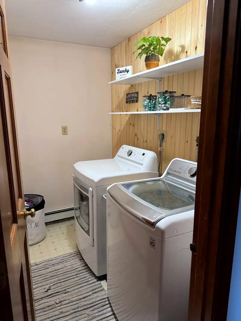 Laundry room with a wood-paneled wall and open shelves